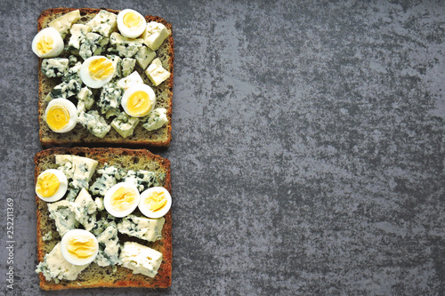 Keto toasts with blue cheese and quail eggs. Healthy wheat rye toasts with cheese and egg.