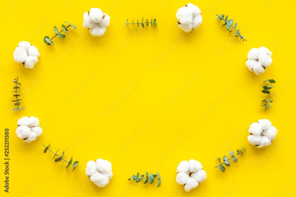 Flowers frame with fresh eucalyptus branches and cotton on yellow background top view space for text