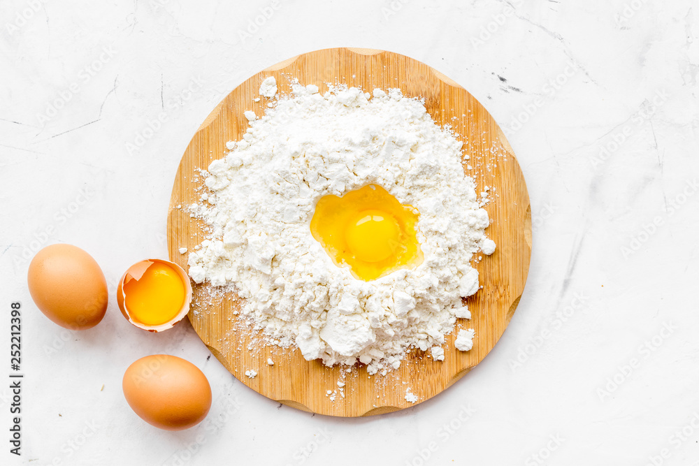 Making dough concept. Pile of flour and eggs on white background top view Making dough concept. Pile of flour and eggs on white background top view