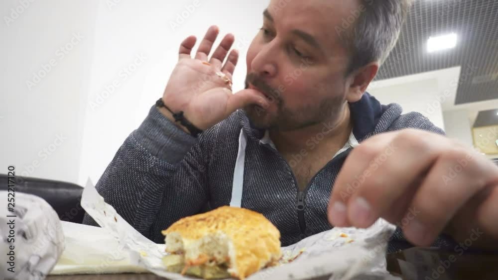 Hungry man eating big hamburger in fast food cafe Hungry man eating big hamburger in fast food cafe