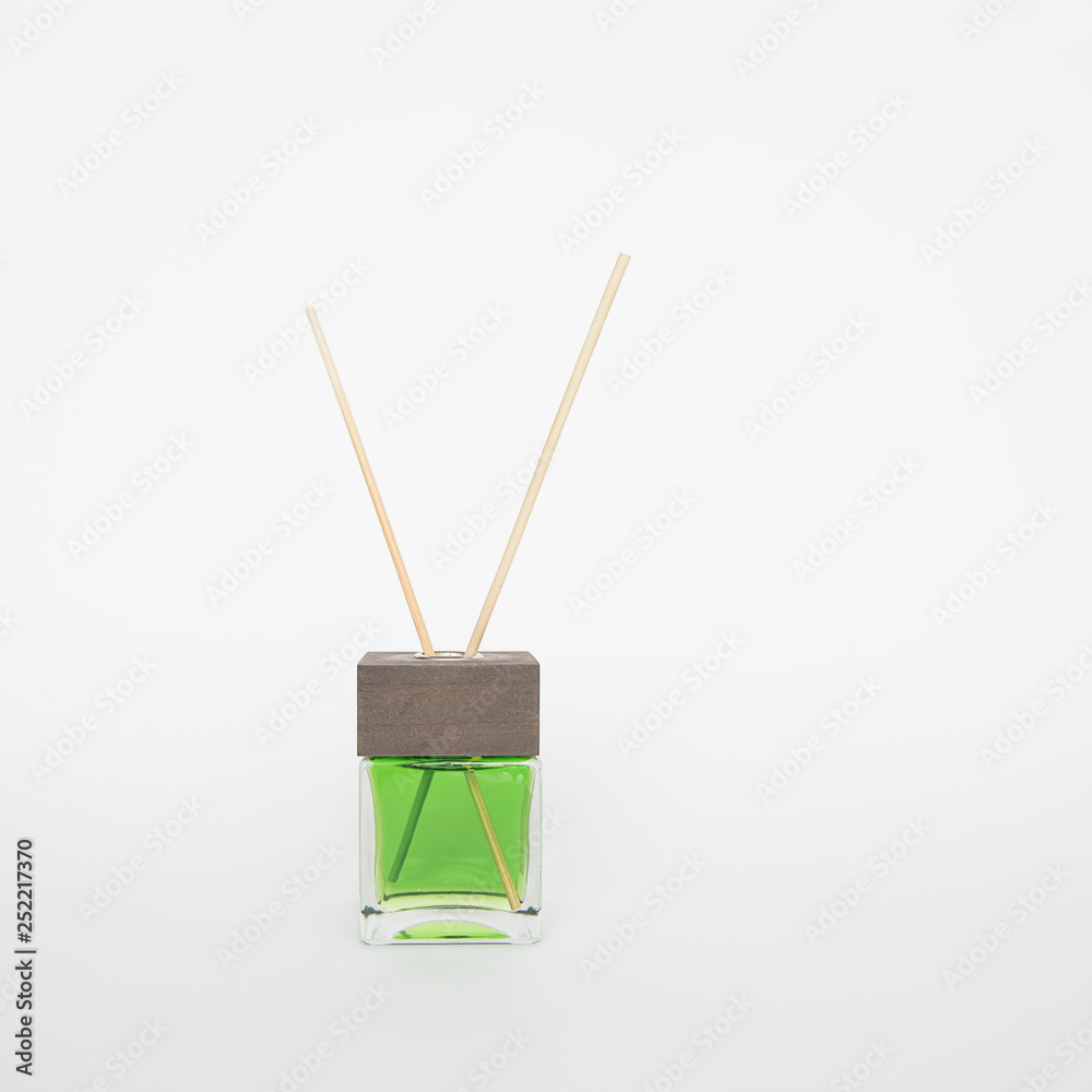 Aroma green liquid in glass bottle with reed sticks isolated on white background. Aroma reed diffuser. Aroma green liquid in glass bottle with reed sticks isolated on white background. Aroma reed diffuser.