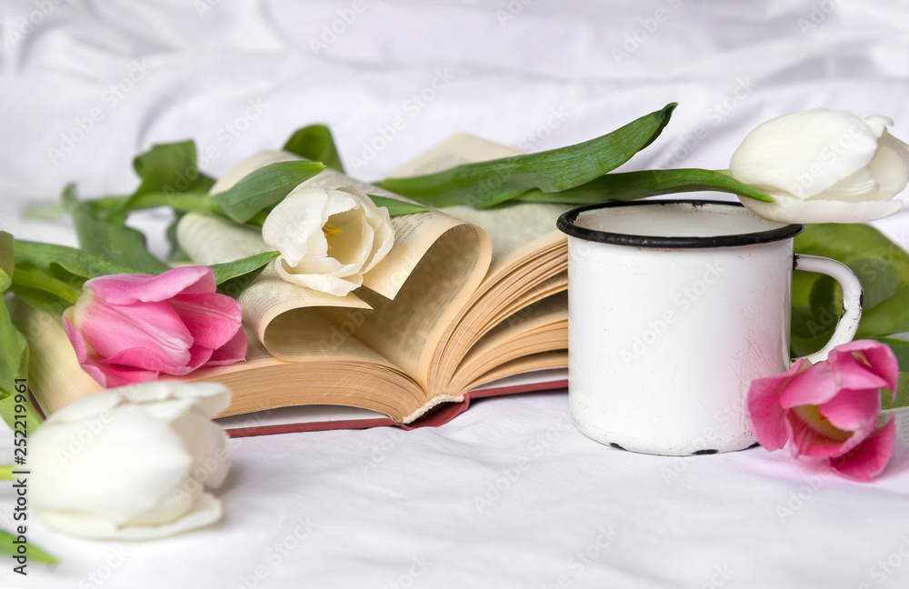 white and pink tulips, white mug on white sheet, open book white and pink tulips, white mug on white sheet, open book