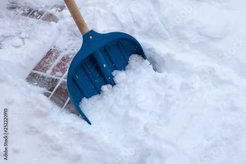 Cleaning snow with shovel in winter day 