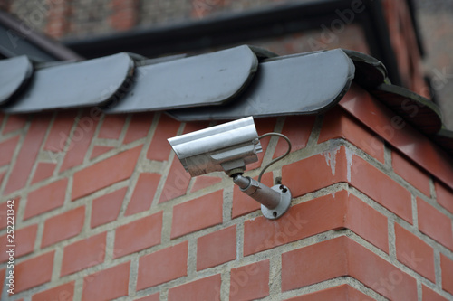 Outdoor silver security camera on a brick wall