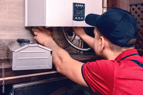 A young skilled worker regulates the gas boiler before use.