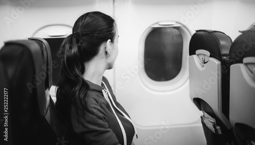 Young happy woman on airplane board. Black and white photo