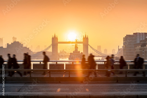 Rush Hour in London bei Sonnenaufgang: Leute laufen hastig zur Arbeit mit Blick auf die Tower Bridge photo