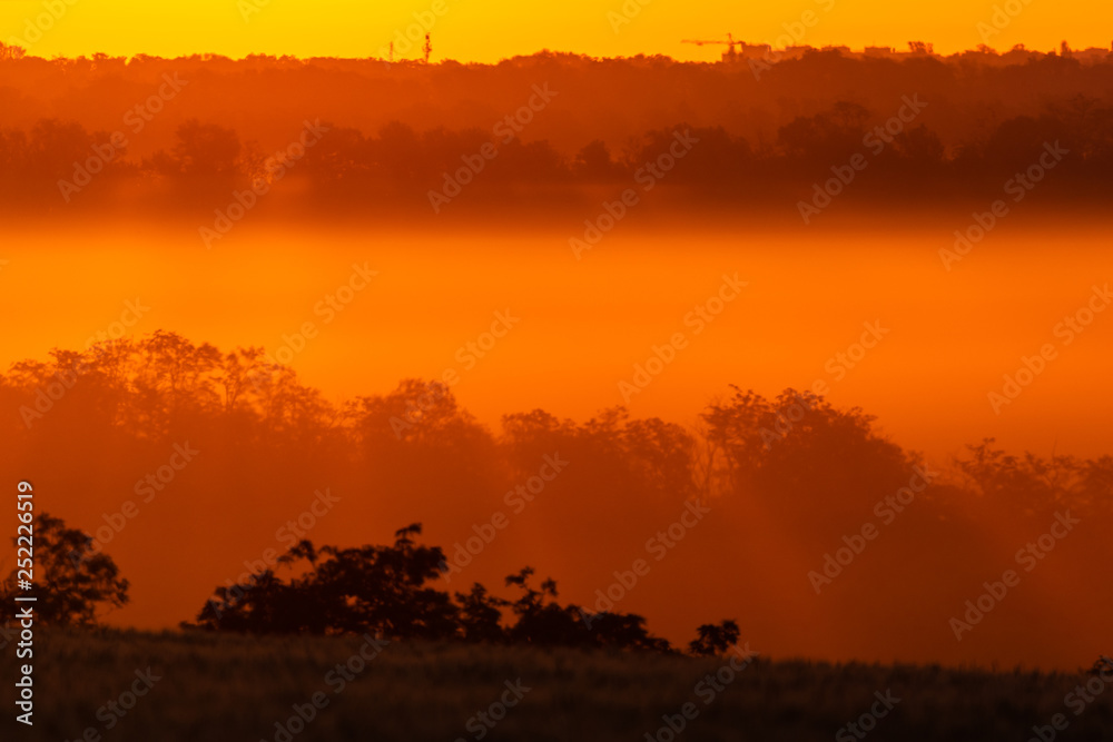 Golden and orange sunrise iluminating a hills and fields