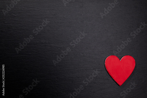Rotes Herz aus Holz auf dunkler Steinplatte