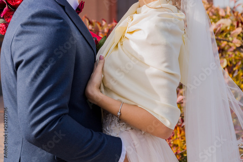 bride and groom stand together in the park in autumn