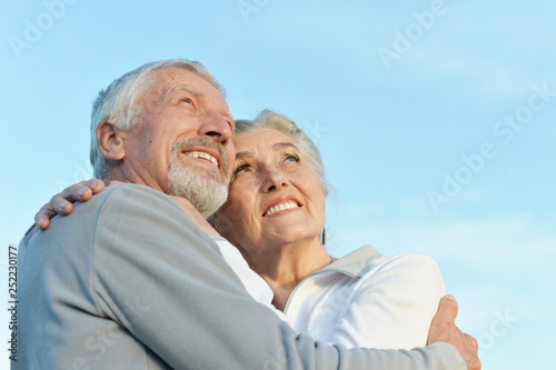 Portrait of happy senior couple hugging against blue sky