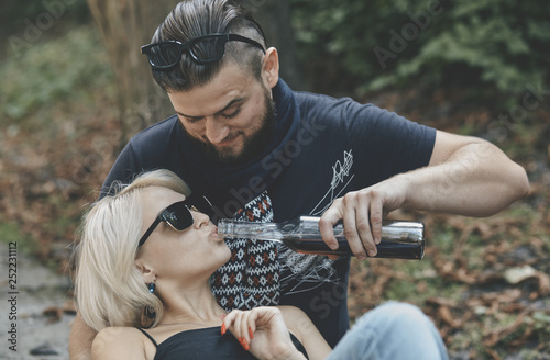 Alco addiction concept. Depressed and hopeless couple sitting after using drunk alcohol on the street photo