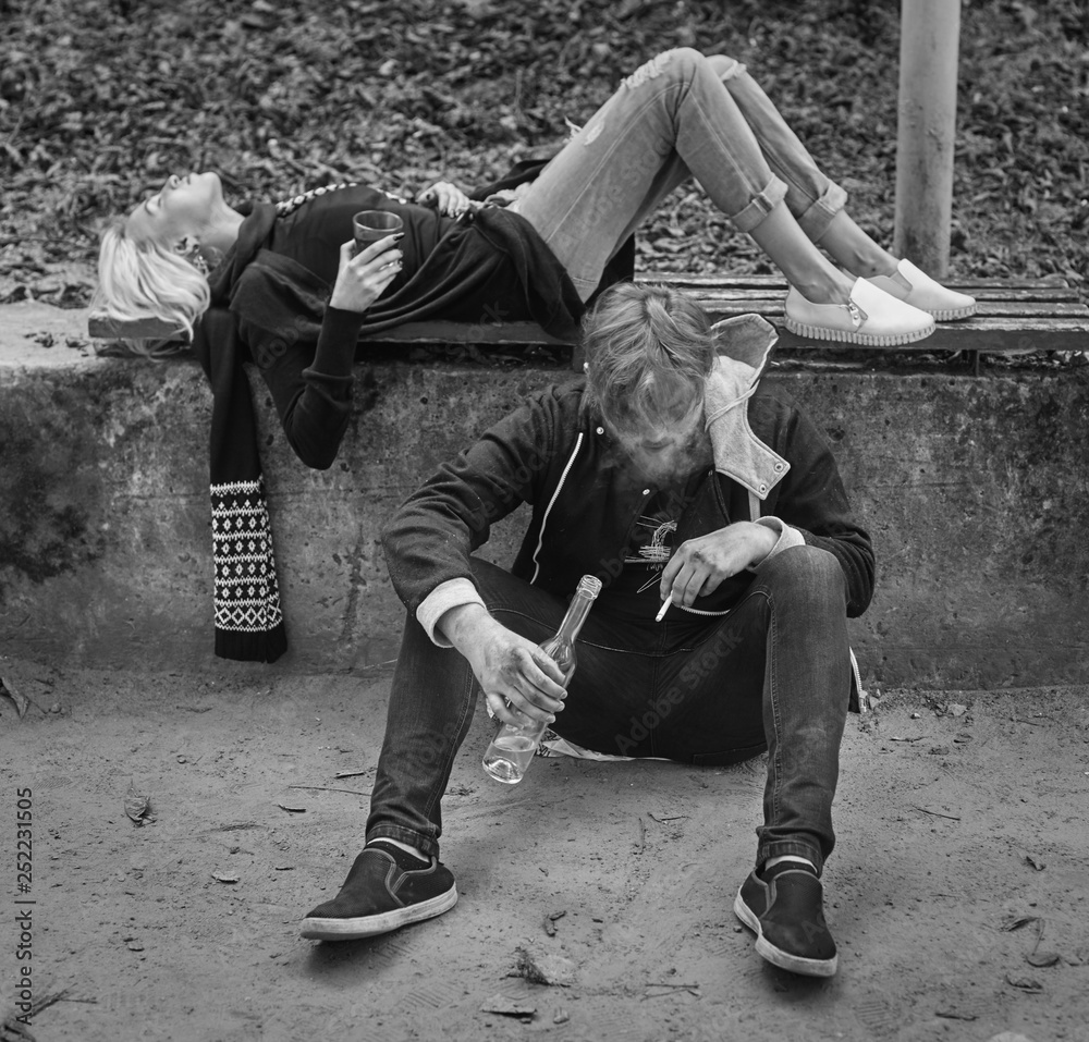 Fototapeta premium Alco addiction concept. Depressed and hopeless couple sitting after using drunk alcohol on the street