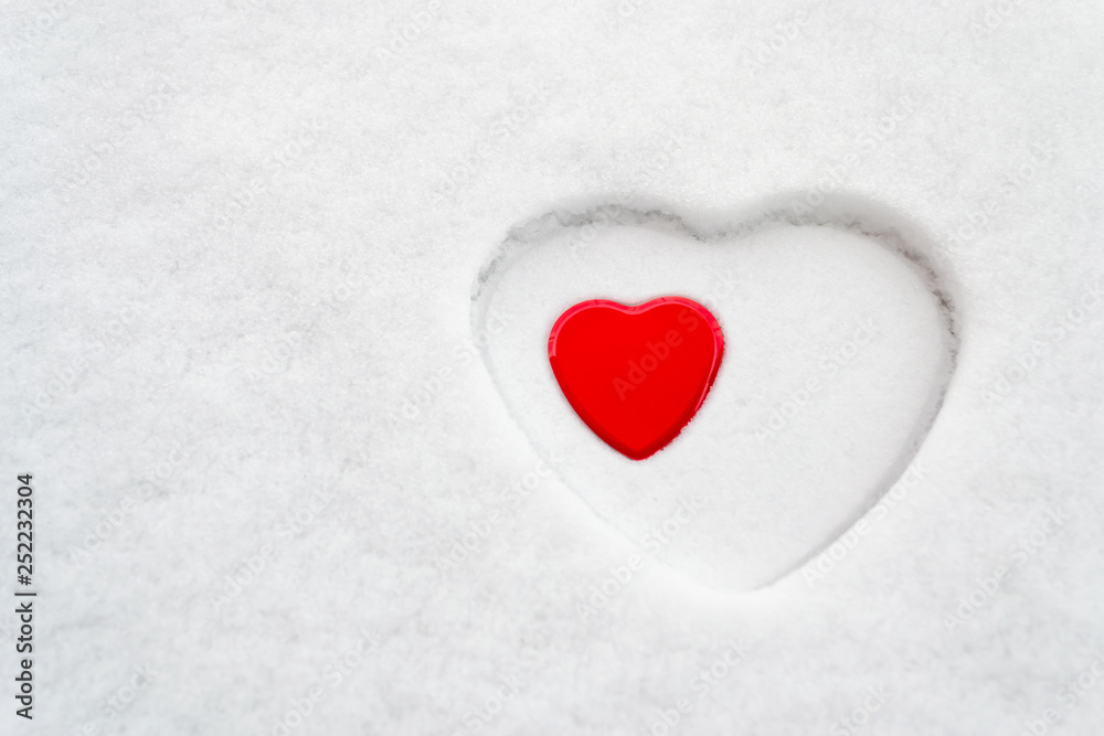 Big white heart outline in snow with a smaller red heart placed inside. Concept for: love, acceptance, motherhood, mother's day, women's day, peace, romance.