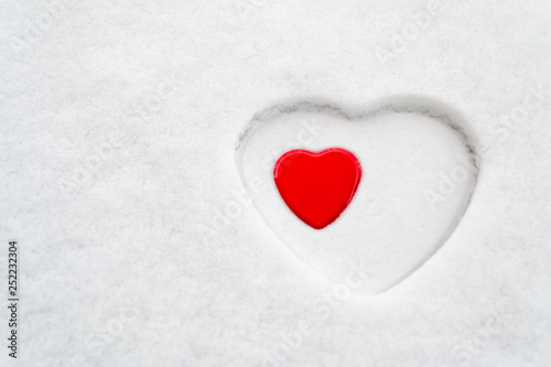 Big white heart outline in snow with a smaller red heart placed inside. Concept for  love  acceptance  motherhood  mother s day  women s day  peace  romance.