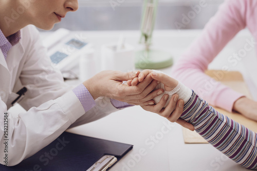Pediatrician examining a young girl with an injured wrist