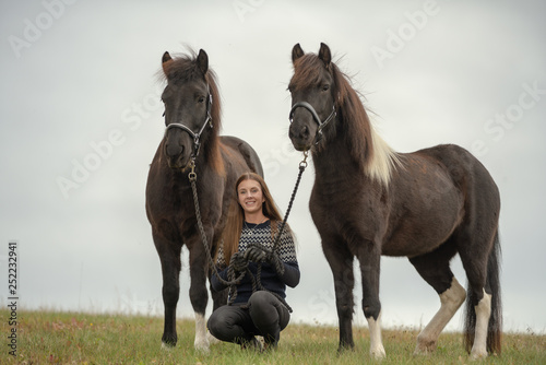 Young Swedish woman in a field with her two Icelandic horses photo