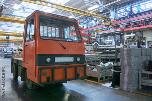a small old electric truck that runs on batteries to deliver parts on a conveyor belt in a huge factory