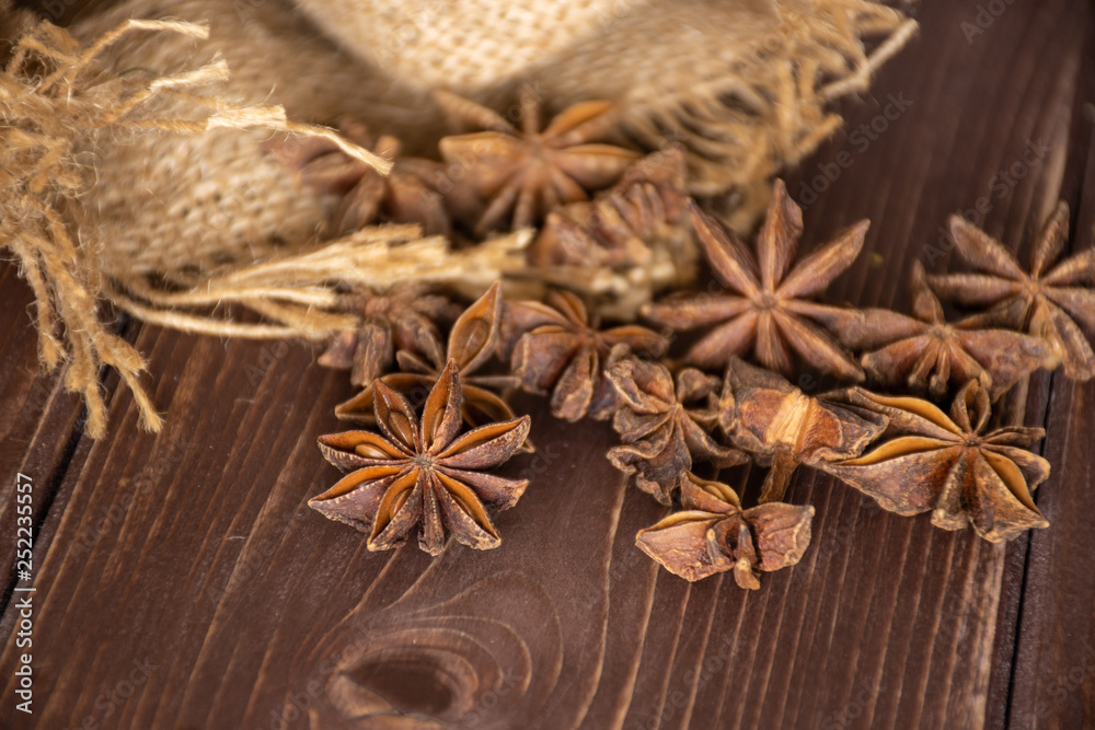 Obraz premium Lot of whole dry brown star anise fruit in a jute bag on brown wood