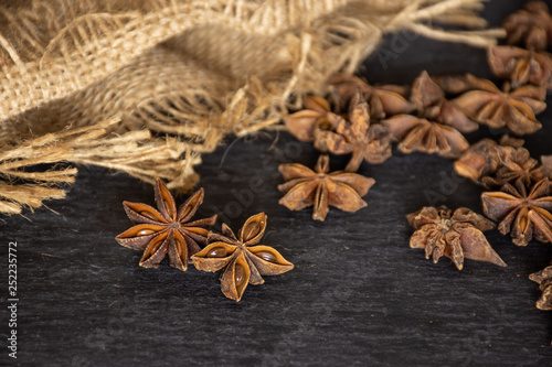 Lot of whole dry brown star anise fruit on jute cloth on grey stone photo