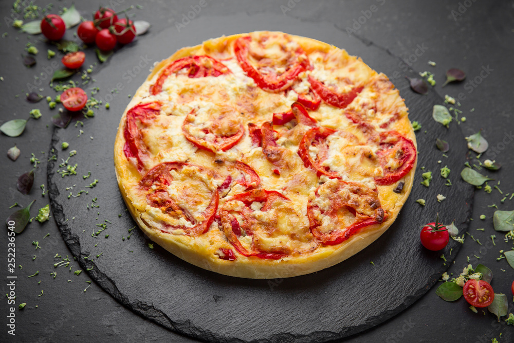 Traditional quiche pie with tomatoes, mozzarella and spinach.