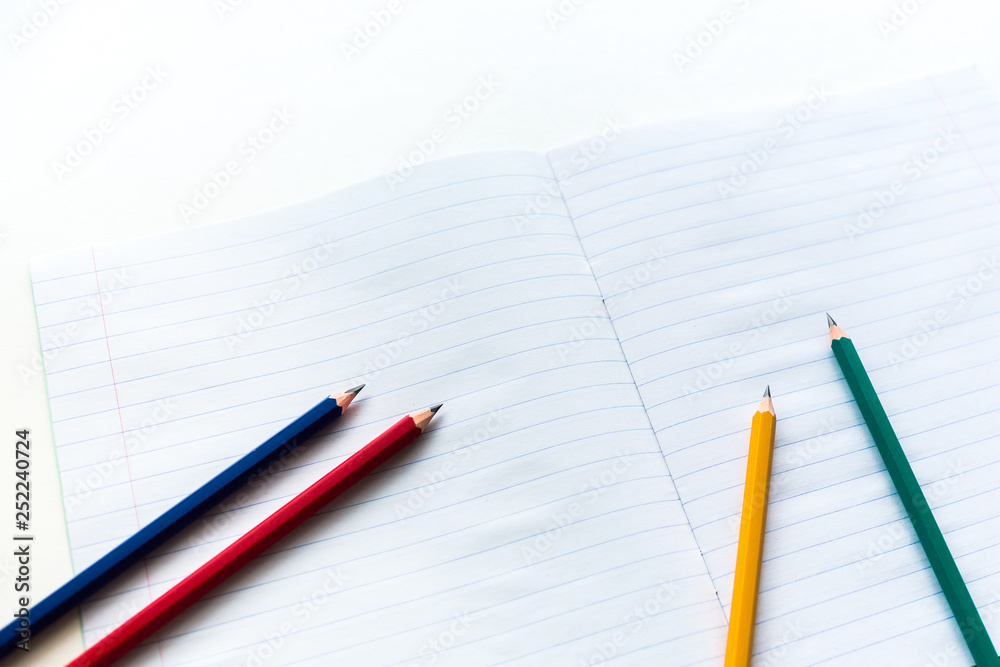  Multicolored pencils on notebook in a ruler
