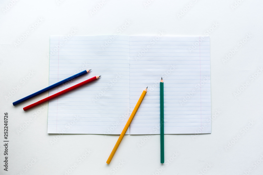 Multicolored pencils on notebook in a ruler Multicolored pencils on notebook in a ruler