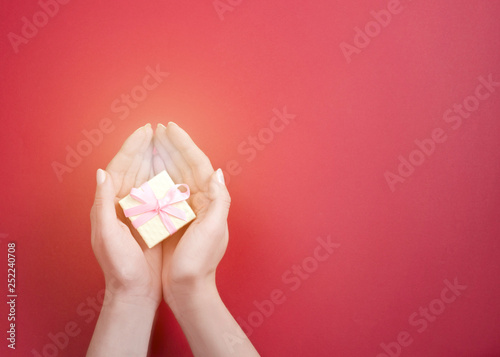 A small gift with a pink bow in women's hands photo