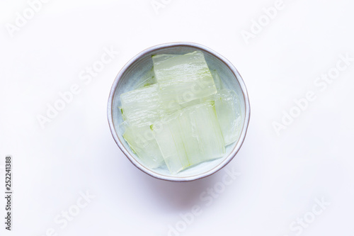 Aloe vera gel slices in ceramic bowl on white.