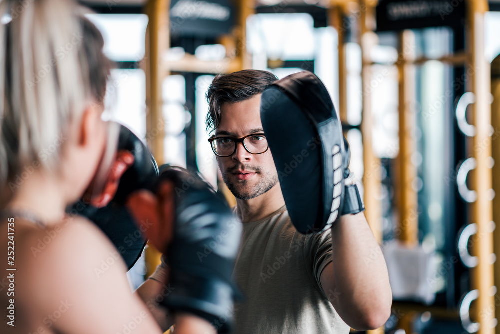 Fototapeta premium Young woman on kickboxing training with her coach.