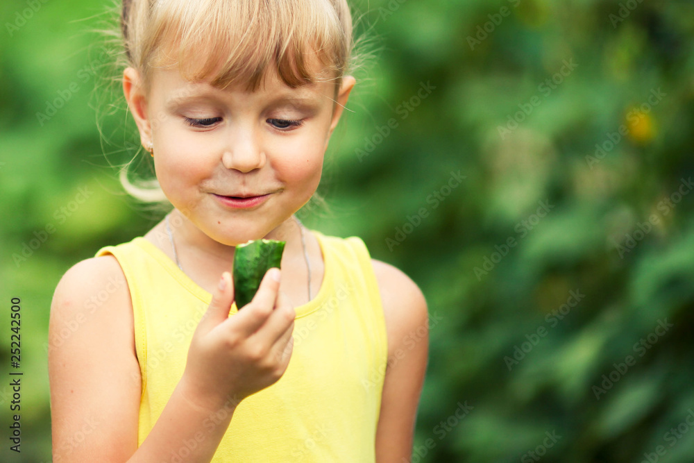Portrait of a little girl surprised looking at a cucumber Portrait of a little girl surprised looking at a cucumber
