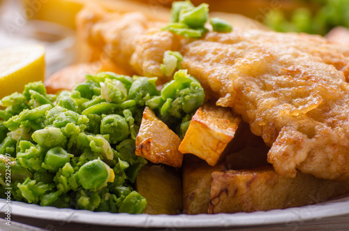 Fotografia Traditional British street food fish and chips with mushy peas on paper plate