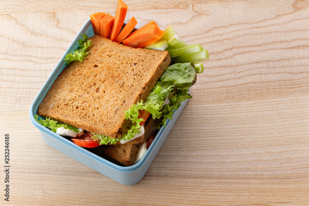 Flat lay with healthy sandwich in plastic container on wooden table. Daily office or school lunch concept Flat lay with healthy sandwich in plastic container on wooden table. Daily office or school lunch concept