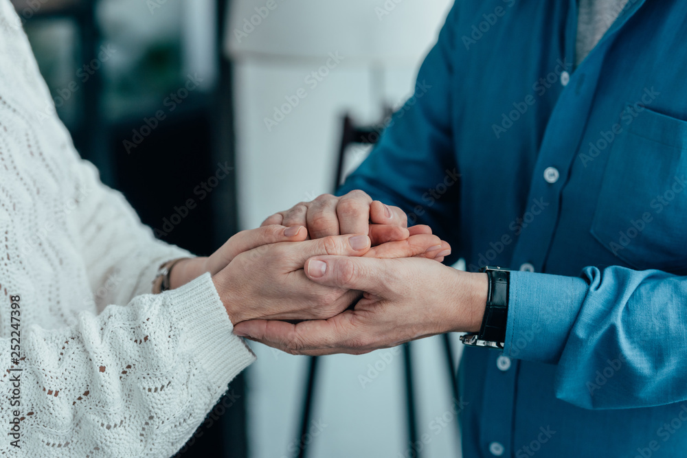 cropped view of couple holding hands at home