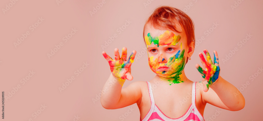 Humorous portrait of little cute child girl with children's makeup and painting colorful hands.People, childhood, art concept