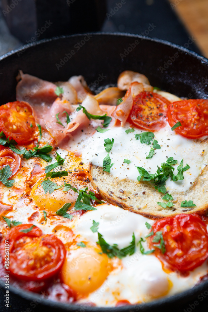 Fried eggs with bacon, toast and tomatoes in a pan Fried eggs with bacon, toast and tomatoes in a pan