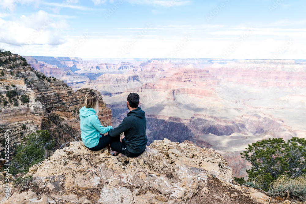 Couple sitting on the edge of a canyon and looking down to the canyon