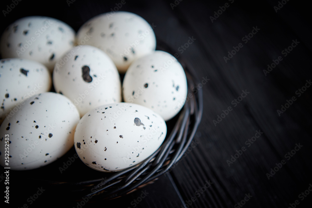 Whole Chicken eggs in a nest on a black rustic wooden background. Easter symbols Whole Chicken eggs in a nest on a black rustic wooden background. Easter symbols