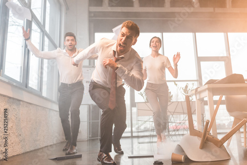 businesspeople running and screaming in office with smoke