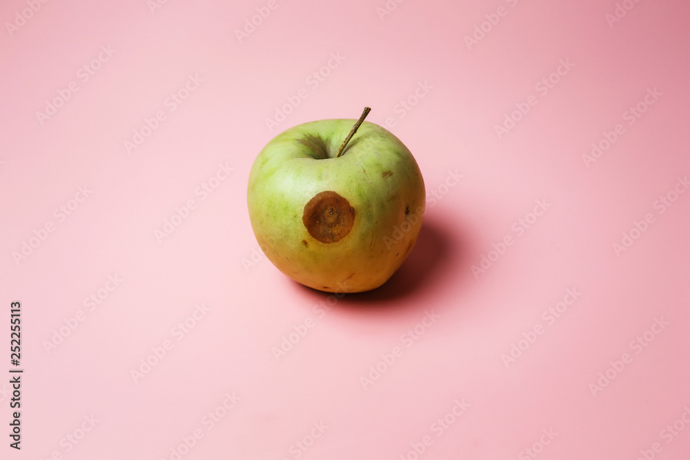 rotten green apple on a pink background. concept of spoiled food and ...