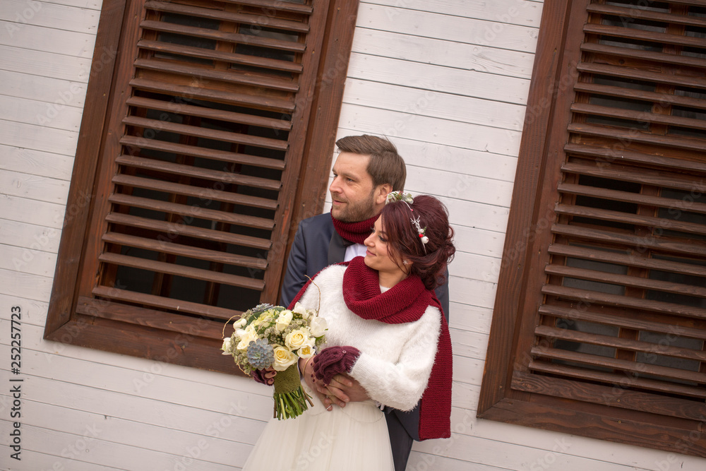 Beautiful wedding couple with neckclouds posing in front of white house Beautiful wedding couple with neckclouds posing in front of white house