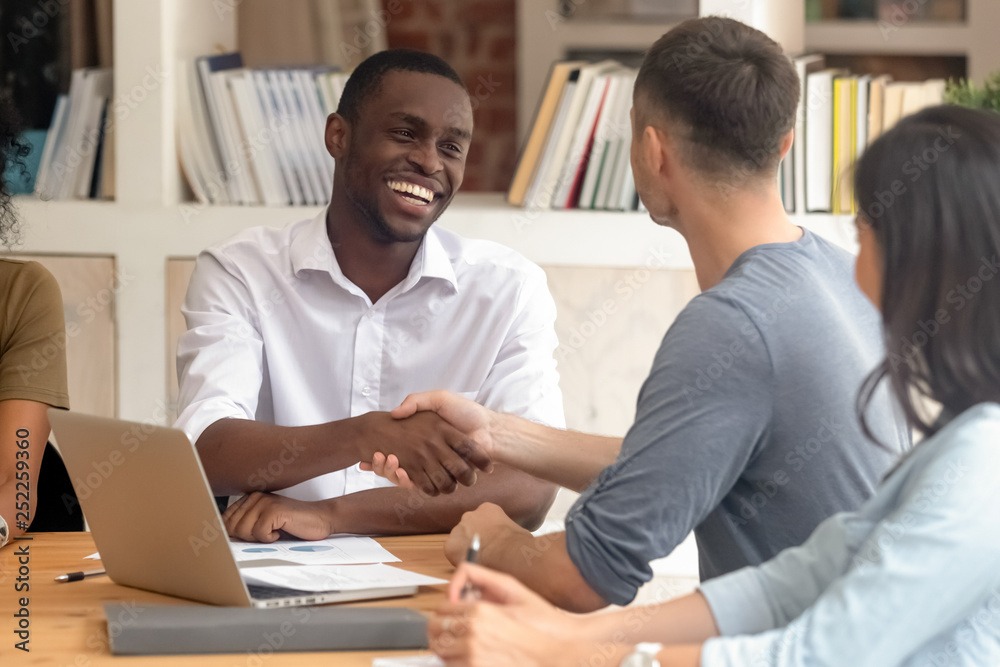 © fizkes - Happy african businessman handshaking partner at office group meeting © fizkes - Happy african businessman handshaking partner at office group meeting