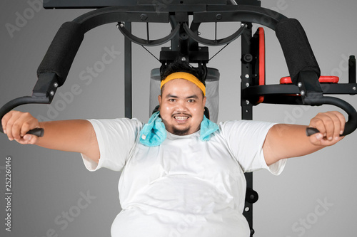 Happy fat man exercising with a fitness machine