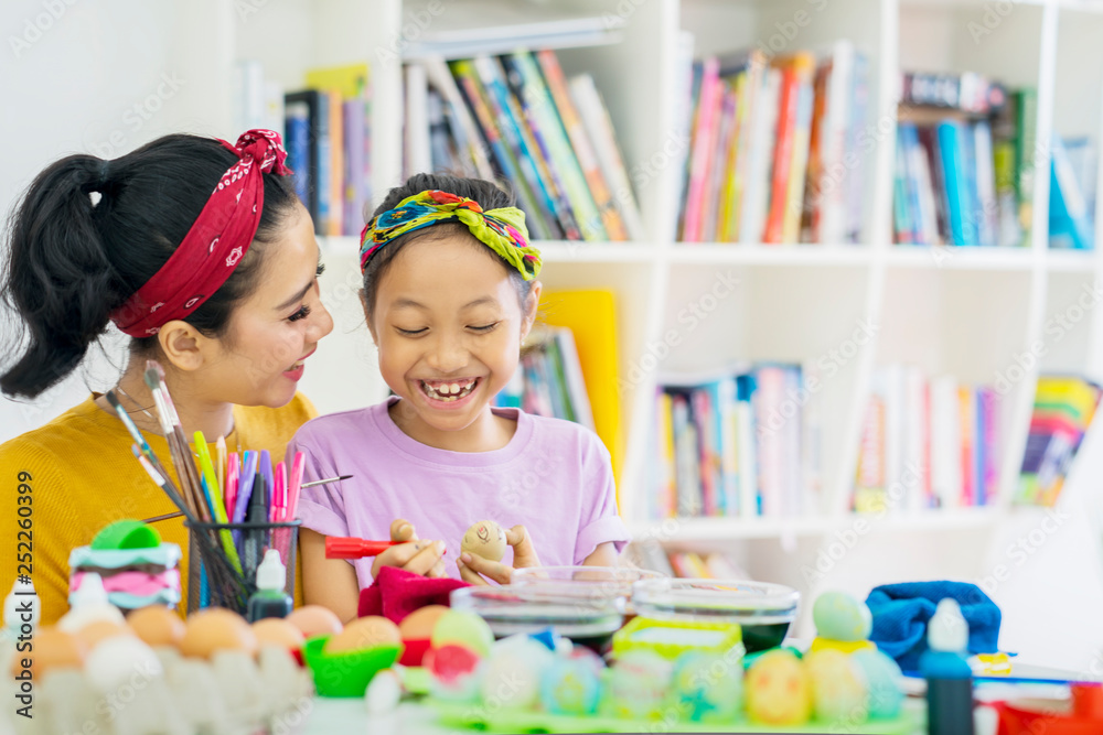 Fototapeta premium Happy little girl helped by her mother to dye eggs
