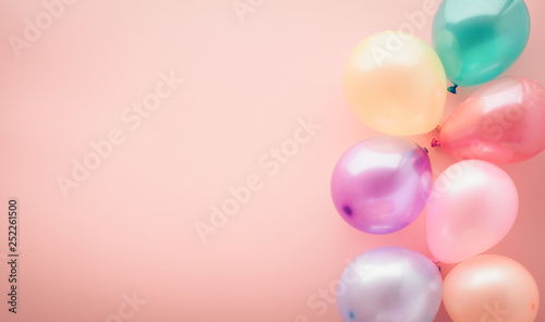 Party concept background, colorful balloons on pastel pink table, top view, copy space for text, selective focus