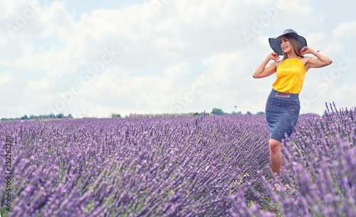 Girl in hat in lavender flowers field.