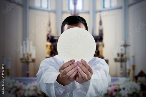 Pastor holding a sacramental bread in church photo