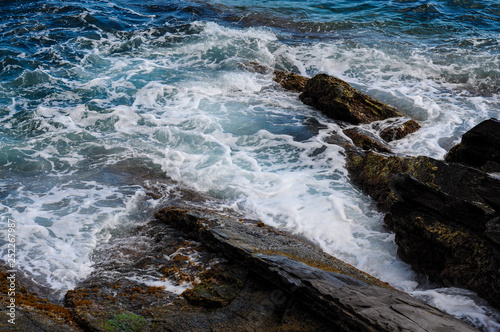 Spienione morskie fale i skały na wybrzeżu morza we włoszech. Niebieskie morze w środku włoskiego lata
