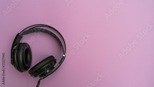 Black headphones on pink background. Top view