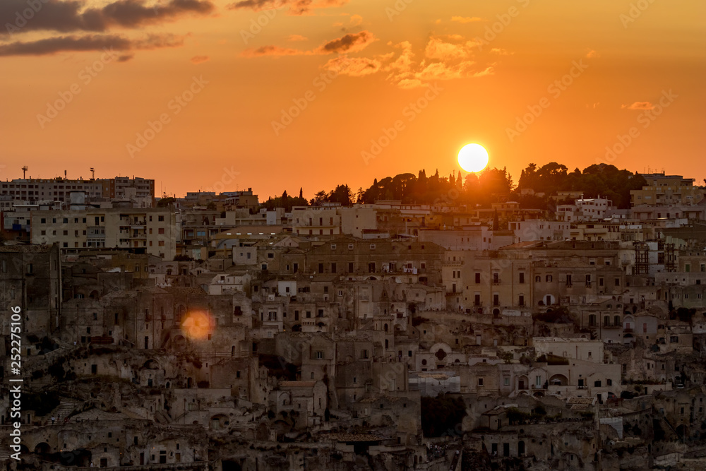 Amazing view while Sun is setting down above the famous tourist destination ancient beautiful town of Matera, the Sassi di Matera, Basilicata, Southern Italy, warm scenery summer evening